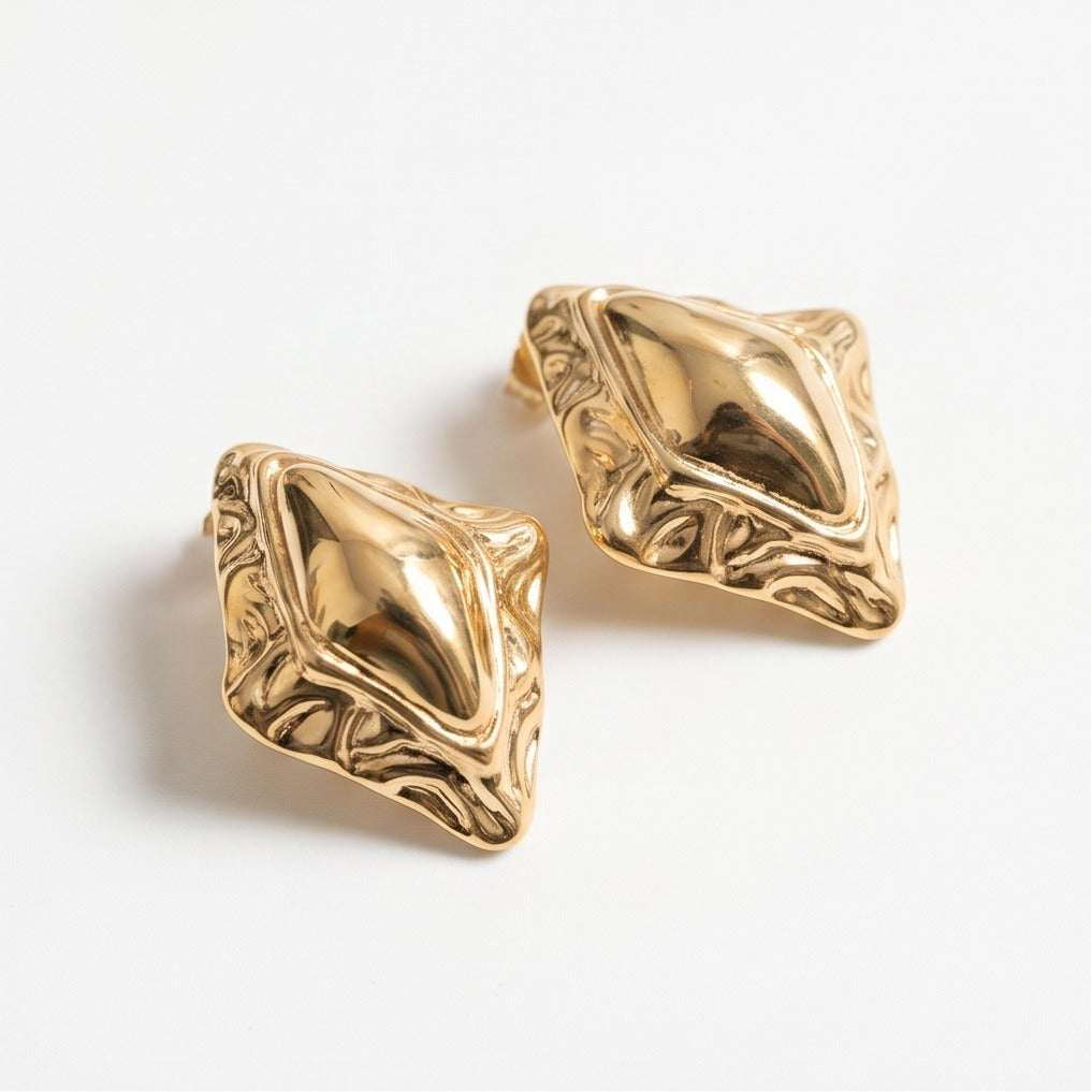 Gold earrings with intricate designs on a white background